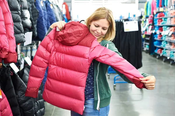 Женщина выбирает зимнюю куртку в магазине — стоковое фото