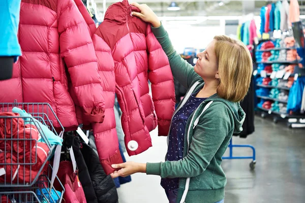 Frau wählt Winterjacke im Geschäft — Stockfoto