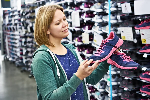 Mujer elige zapatos de correr en la tienda —  Fotos de Stock