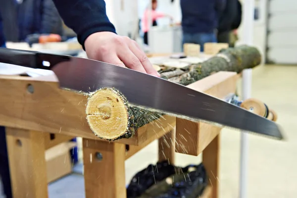 Sierra de mano de madera de aserrado hombre en la mesa de carpintería — Foto de Stock