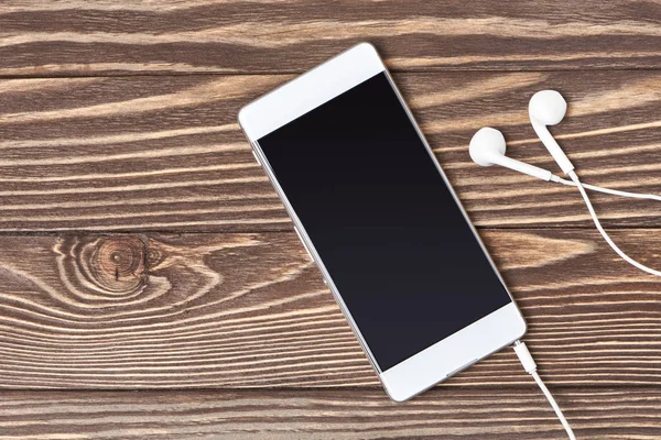 Smartphone y Auriculares sobre fondo de madera —  Fotos de Stock