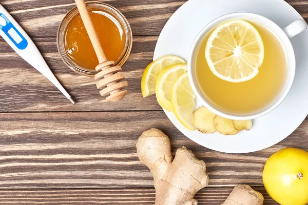 Una taza de té de jengibre, miel, limón, termómetro. Saludable concep — Foto de Stock