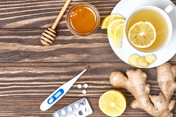 Una taza de té de jengibre, miel, limón, pastillas, termómetro. Estafa saludable — Foto de Stock