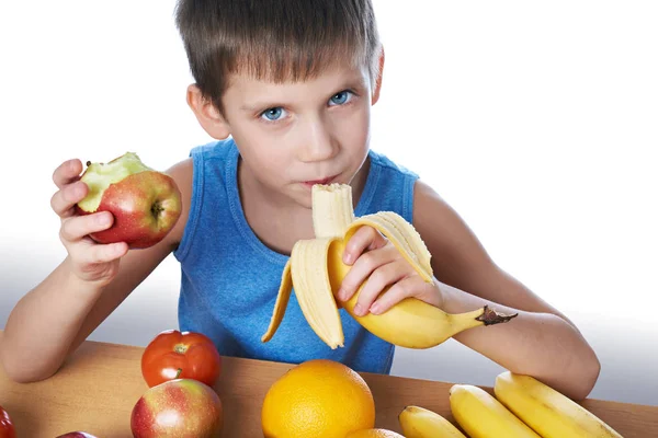 Glücklicher gesunder Junge isst Banane und Apfel isoliert — Stockfoto