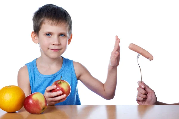 Boy with apples and orange against harmful sausage — Stock Photo, Image
