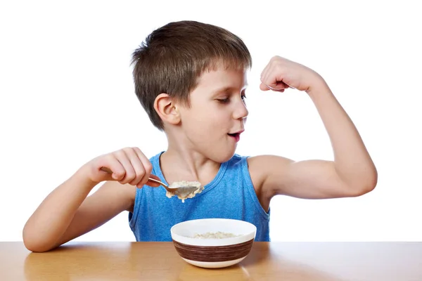 Menino feliz comendo mingau na mesa isolado — Fotografia de Stock