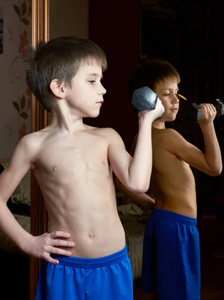 Boy is training with dumbbells near mirror — Stock Photo, Image