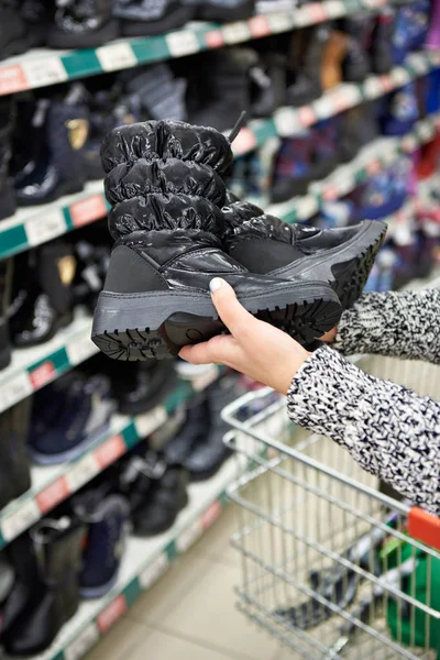 Winter boots in hands of women customers at store — Stock Photo, Image