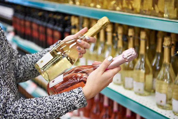 Vrouw met flessen rose en witte wijn in de winkel — Stockfoto