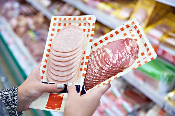 Woman chooses ham in grocery store — Stock Photo, Image