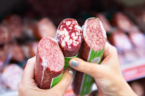 Woman chooses smoked sausage in store — Stock Photo, Image