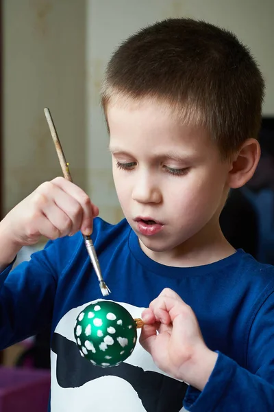 Boy paints a Christmas ball toy — Stock Photo, Image