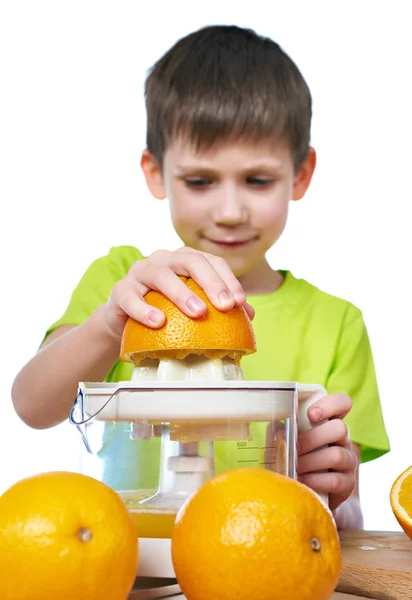 Счастливый мальчик с апельсинами делает сок в соковыжималке изолированы — стоковое фото