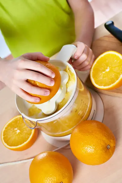 Мальчик с апельсинами делает сок в изоляции соковыжималки — стоковое фото