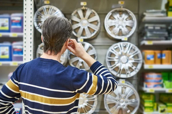Man chooses alloy wheels for your car wheels in supermarket — Stock Photo, Image
