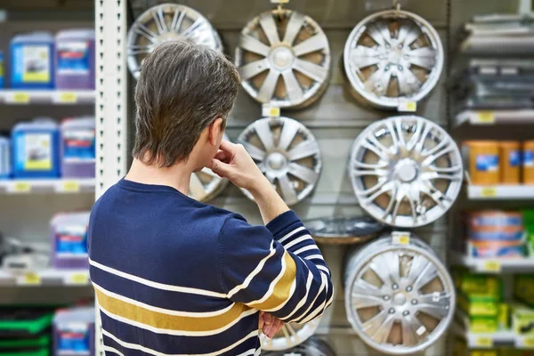 Man chooses alloy wheels for your car wheels in supermarket — Stock Photo, Image