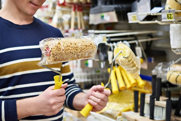 Man kiest verf rollers voor reparatie in winkel — Stockfoto
