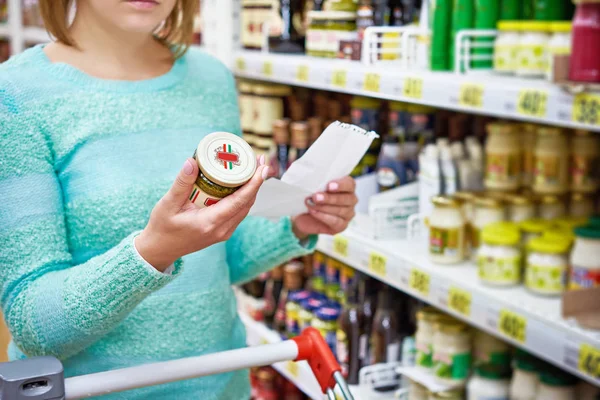 Vrouw kiest kruiden pesto in supermarkt — Stockfoto