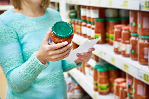 Vrouw kiest lecho tomaat in supermarkt — Stockfoto