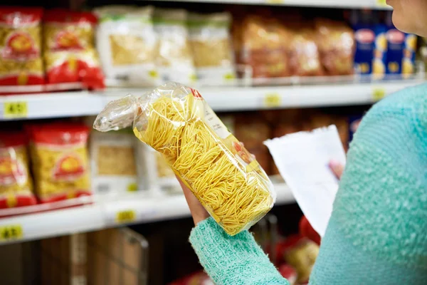 Vrouw met pakket pasta in winkel — Stockfoto