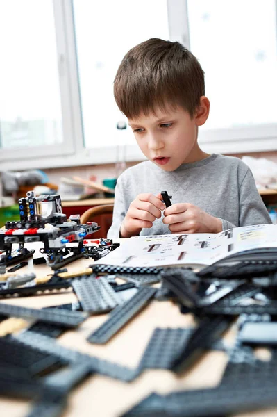 Menino coleciona crianças brinquedos de construção de plástico — Fotografia de Stock