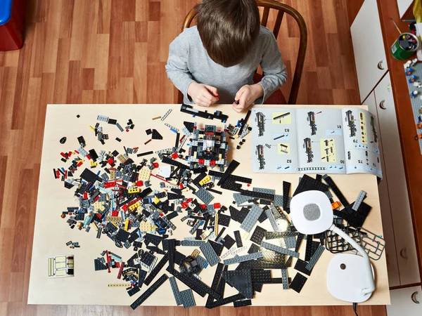 Мальчик играет и собирает детские пластиковые строительные игрушки — стоковое фото