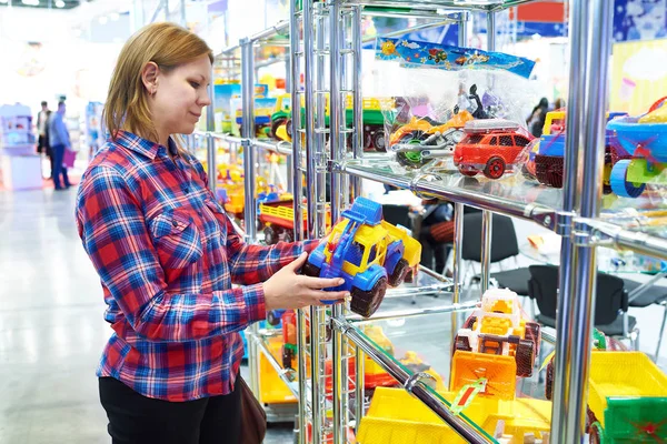 Mujer compra coche de juguete en tienda de niños —  Fotos de Stock