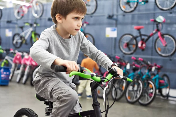 Chico montando bicicleta en tienda de deporte — Foto de Stock