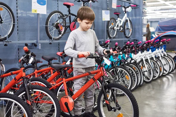 Мальчик выбирает велосипед в спортивном супермаркете — стоковое фото