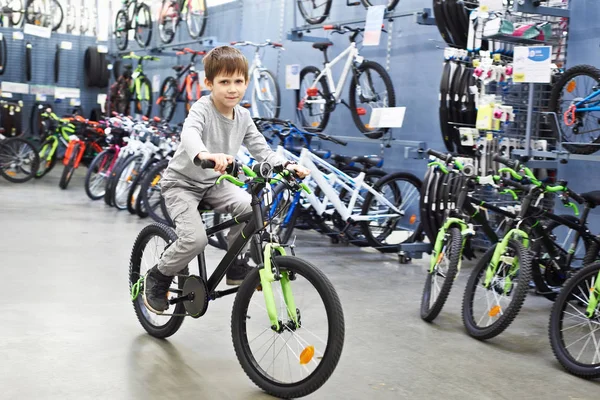 Мальчик на велосипеде в спортивном супермаркете — стоковое фото