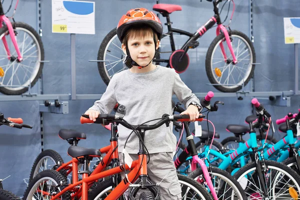 Chlapec v helmě zvolí s kolo ve sportovním obchodě — Stock fotografie