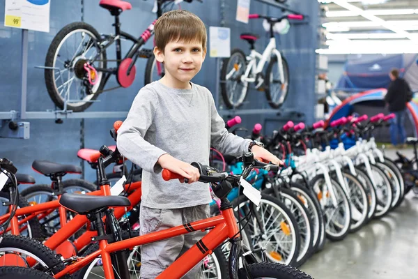 Menino escolhe bicicleta na loja de esporte — Fotografia de Stock