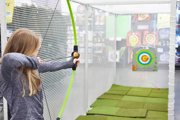 Chica dispara un arco en un campo de tiro para niños — Foto de Stock