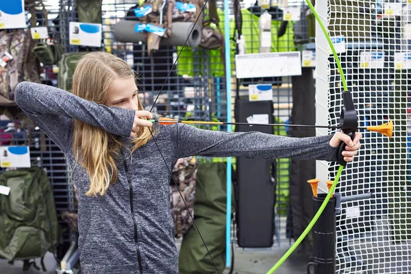 Девочка пробует детский лук в спортивном магазине — стоковое фото