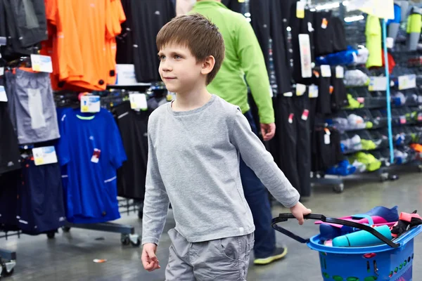 Niño con carrito de compras en tienda de ropa deportiva —  Fotos de Stock