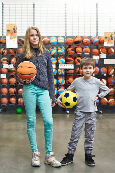 Niño y niña con pelota de fútbol y baloncesto en la tienda — Foto de Stock