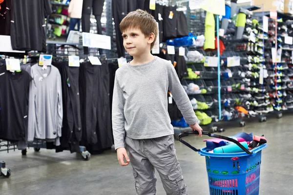 Хлопчик з кошиком в магазині спортивного одягу — стокове фото