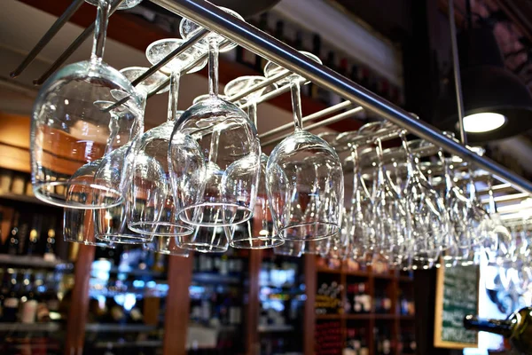 Empty wine glasses hanging above bar — Stock Photo, Image