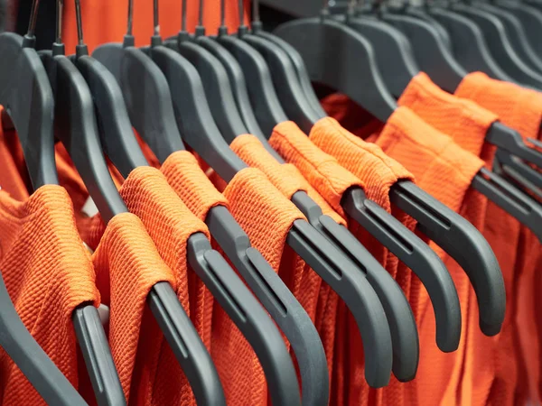 Апельсиновые платья на вешалках — стоковое фото