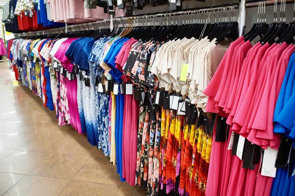 Различные платья на вешалках в магазине — стоковое фото