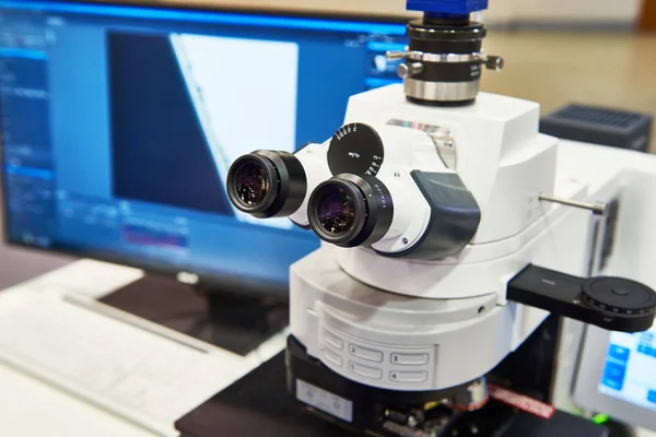 Estereomicroscópio e tela de computador em laboratório de industrial — Fotografia de Stock