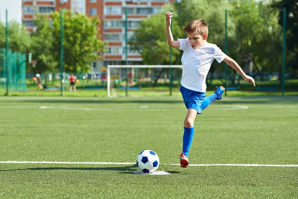 Fiú futballista ugrással, mielőtt rúgni a labdát — Stock Fotó