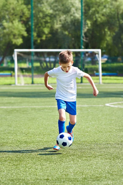 Fiú futball játékos fut a labdával — Stock Fotó