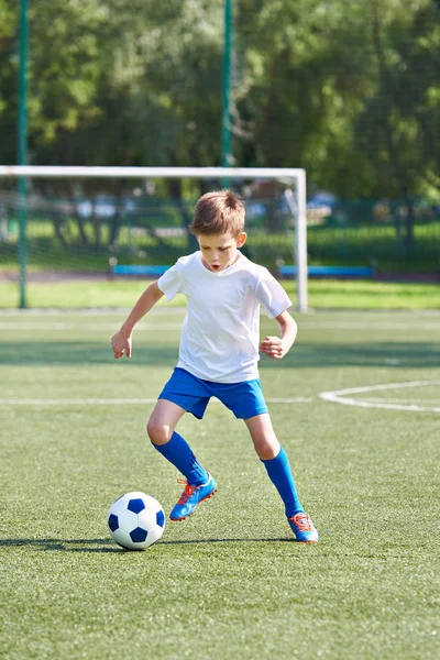 Fiú futball játékos fut a labdával — Stock Fotó