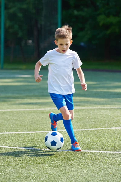 Хлопчик-футболіст біжить з м'ячем — стокове фото