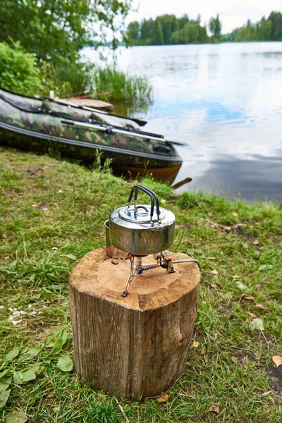 Poêle de randonnée avec bouilloire sur souche et bateau de pêche — Photo
