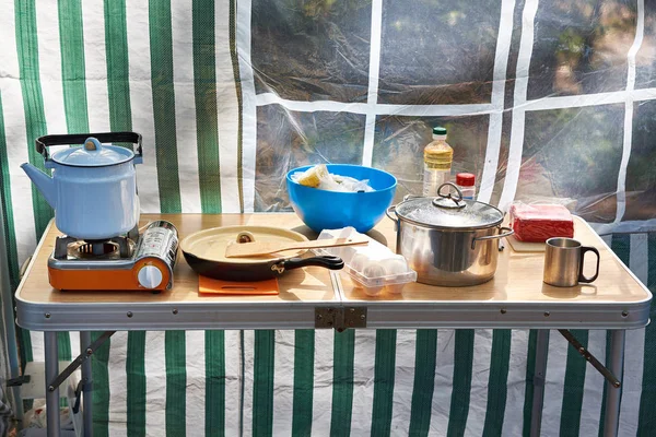 Camping stove with kettle and crockery on table