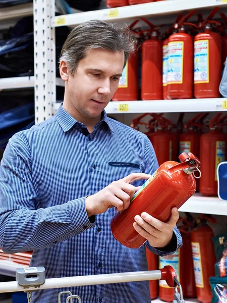 L'homme choisit et achète un extincteur en magasin — Photo