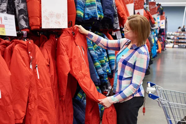 Женщина выбирает лыжный комбинезон в спортивном магазине — стоковое фото