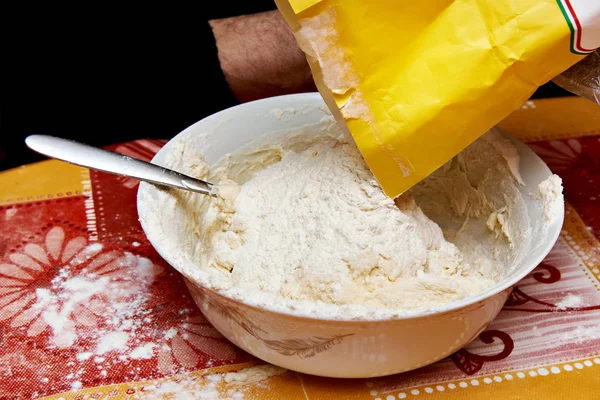 Putting flour from paper bag into bowl with dough — Stock Photo, Image